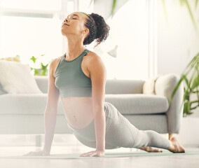 Ill cobra pose myself all the way to cloud nine. Shot of a young woman practising yoga in her living room.