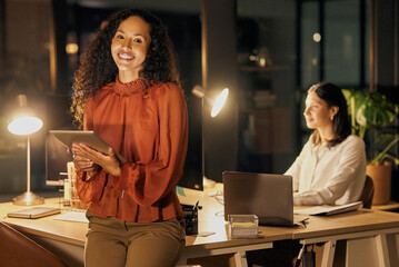 We stayed a little to work at perfecting our plans. Portrait of a young businesswoman using a digital tablet while working in an office at night with her colleague in the background.