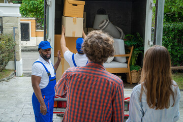 Poster - Happy couple with moving boxes at new house,Moving company employee checks boxes in a truck before sending them to the homeowner.