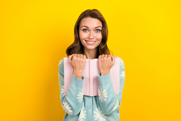 Wall Mural - Portrait of lovely positive girl beaming smile arms hold book isolated on yellow color background