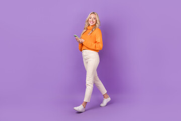 Poster - Full length profile photo of lovely positive person hold smart phone walking isolated on violet color background