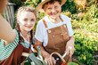 © Iryna - Senior female gardener in straw hat and her lovely granddaughter making selfie photo in farm or garden ar sunny summer hot day outdoor.