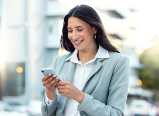 Canvas Print - Another day, another connection made. Shot of a young businesswoman using a smartphone against an urban background.