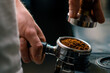 © Guys Who Shoot - A professional barista in a coffee shop prepares ground coffee by tamping fresh ground coffee beans close-up