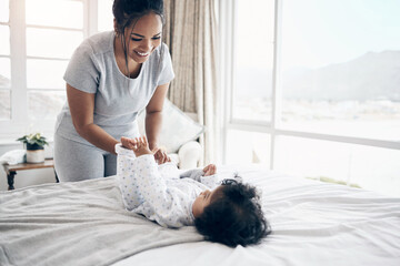 Sticker - Enjoying her growth. Shot of a young mother changing her baby girl at home.