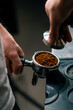 © Guys Who Shoot - A professional barista in a coffee shop prepares ground coffee by tamping fresh ground coffee beans close-up