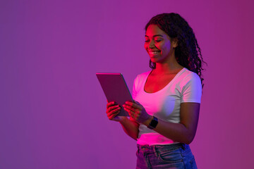 Poster - Black Woman Standing in Neon Light And Browsing Internet On Digital Tablet