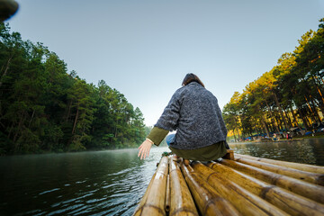  solo asian woman travel by thai local bamboo boat in tropical forest and lake in autumn season