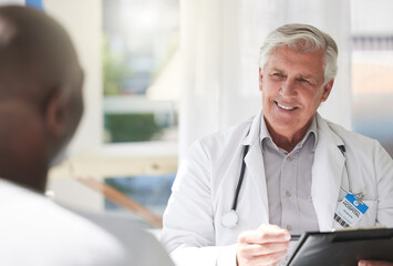 Poster - He lives and breathes healthcare. Shot of a mature doctor having a checkup with a patient at a hospital.