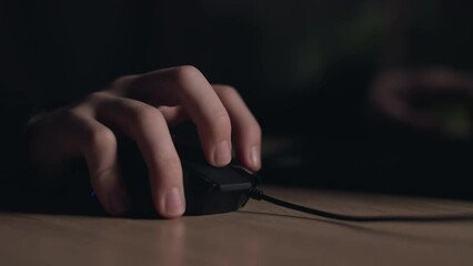 Close up of man gamer hands using computer mouse is playing video game at night. Male hacker breaks into system, coding or data analysis programmer, developer or employee on tech for software code.