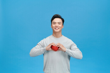 Wall Mural - Young man holding a red heart shaped toy