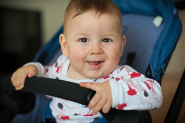 Wall Mural - Portrait of happy and smile baby boy in his pram baby carriage, looking at camera. Joy and happiness concept. Love and family emotion