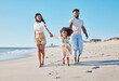© Nina L/peopleimages.com - Come this way. Full length shot of an affectionate young family of three taking a walk on the beach.