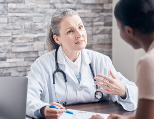 Canvas Print - Making sure her patient understands every detail of the diagnosis. Shot of a doctor going through paperwork during a consultation with a patient in a medical office.