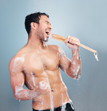 One Young Muscular Mixed Race Man Singing In The Shower Against A Blue Studio Background. Cheerful Hispanic Guy Having Fun With A Shower Brush As A Mic Doing His Morning Hygiene Routine In The Shower