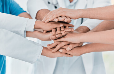 Poster - Improving patient outcomes together. Closeup shot of a group of medical practitioners joining their hands together in a huddle in a hospital.