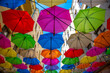 Ulica Piotrkowska w Łodzi i kolorowe parasole wiszące między budynkami nad błękitnym niebem.