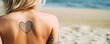 © XaMaps - A blonde woman on vacation on the beach features a heart tattoo on her bare back, inviting love and inspiration. Generative AI