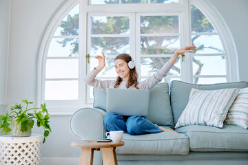 Wall Mural - Get lost in your favourite song. Full length shot of an attractive young woman listening to music while relaxing on the sofa at home.