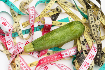 Zucchini with measuring tape on white background