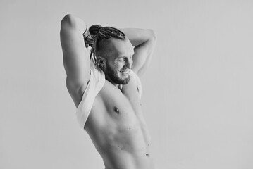 Monochrome portrait handsome caucasian athletic laughting young man taking off white t-shirt. Fitness, bodybilding, youth concept