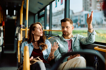 Wall Mural - Young couple arguing while riding in bus.