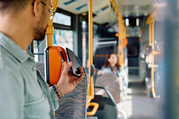 Wall Mural - Close up of man paying with cell phone while onboarding in public transport.