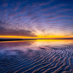 Wall Mural - a seascape during sunset. lines of sand on the seashore. bright sky during sunset. a sandy beach at 