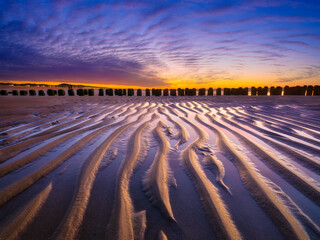 Wall Mural - a seascape during sunset. lines of sand on the seashore. bright sky during sunset. a sandy beach at 