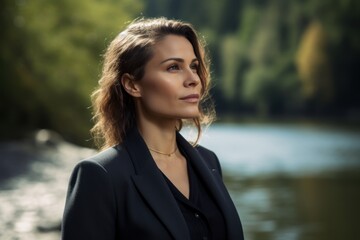 Lifestyle portrait photography of a satisfied woman in her 30s wearing a classic blazer against a peaceful river or stream background. Generative AI