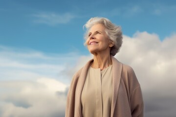 Studio portrait photography of a pleased woman in her 60s wearing a chic cardigan against a sky and clouds background. Generative AI