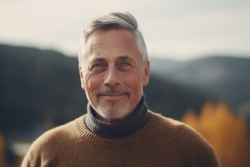 Portrait of handsome senior man with grey hair and beard wearing sweater looking at camera.