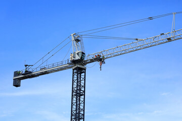 Looking up at a tall tower crane as it constructs a new high rise building. 