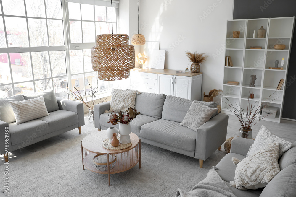Interior of cozy living room with grey sofas and vases on coffee table