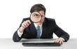 © BillionPhotos.com - Businessman looking in a magnifying glass and working on a keyboard