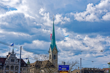 Skyline of the old town at City of Zürich with city hall and church Women's Minster with flag decoration on a blue cloudy spring day. Photo taken April 17th, 2023, Zurich, Switzerland.