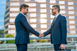 © Volodymyr - Greeting, dealing, merger and acquisition concept. Handshake between two business men. Two businessmen shaking hands on city street. Business men in suit shaking hands outdoors. Business team.