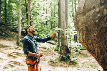 man standing near the rock and belaying the climber,belay device and rope in climber's hands