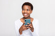 Charming african woman with short haircut holding cellphone in hands chatting messaging with someone boyfriend friends family holding new modern device in arms.