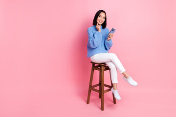 Poster - Photo of thoughtful dreamy woman dressed knit pullover look empty space offer finger on chin hold phone isolated on pink color background