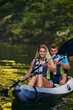 © .shock - A young couple enjoying an idyllic kayak ride in the middle of a beautiful river surrounded by forest greenery