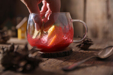 Poster - Tea with herbs, berries and fruits in a transparent cup on a wooden background