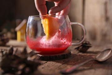 Poster - Tea with herbs, berries and fruits in a transparent cup on a wooden background