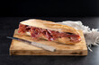 Spanish serrano ham sandwich on black slate background