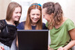© danmorgan12 - Youth Lifestyle. Three Young Happy Laughing Caucasian Girlfriends With Personal Laptop Computer Indoors