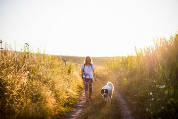 woman walking with dog by the lake at sunset