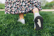 Woman Walking On The Grass. Sportive Shoes, Sneakers Soles On Green Grass At Summer Landscape.