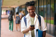 © Monkey Business - Male Secondary Or High School Student Outdoors At School Going To Class Looking At Mobile Phone