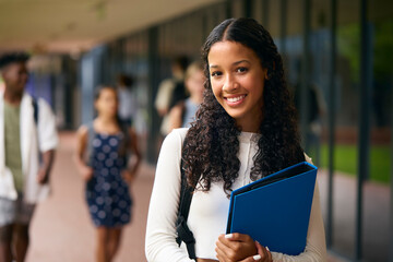 portrait of female secondary or high school student outdoors at school walking to class