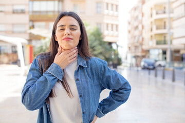 pretty young adult woman feeling ill with a sore throat and flu symptoms, coughing with mouth covered